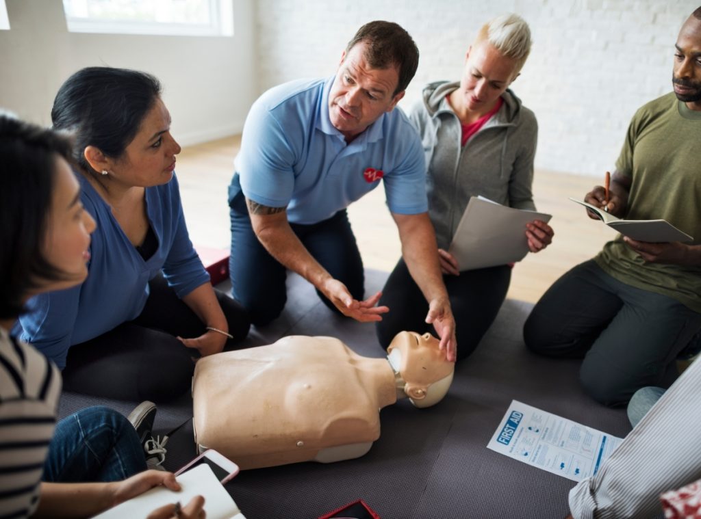 curso de primeiros socorros - equipe reunida tendo aula com instrutor