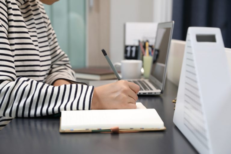 plataforma online - mão de uma mulher escrevendo em caderno