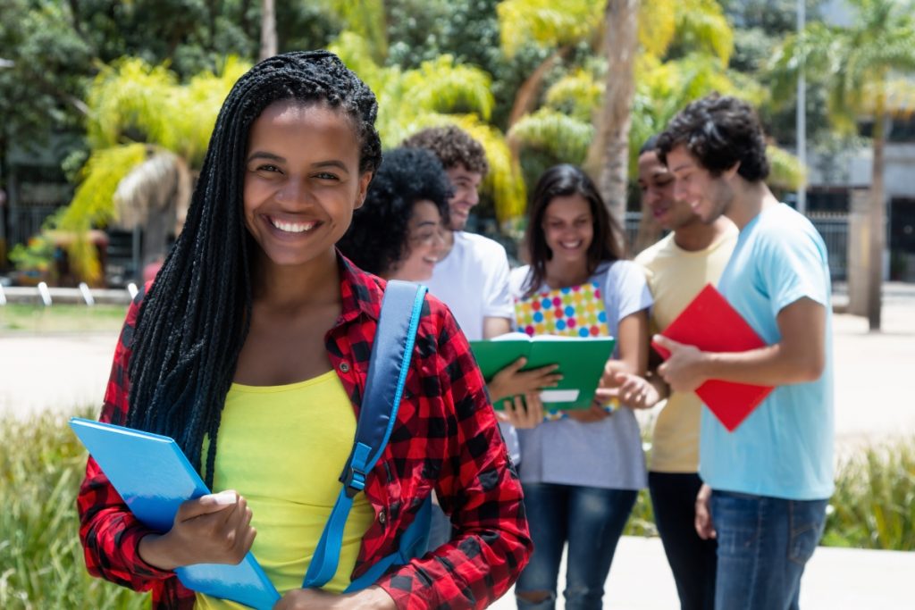 ifsp - estudante negra sorrindo para a câmera e grupo de alunos ao fundo conversando