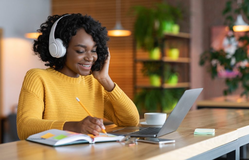 novotec virtual - jovem com fone de ouvido mexendo no computador e sorrindo