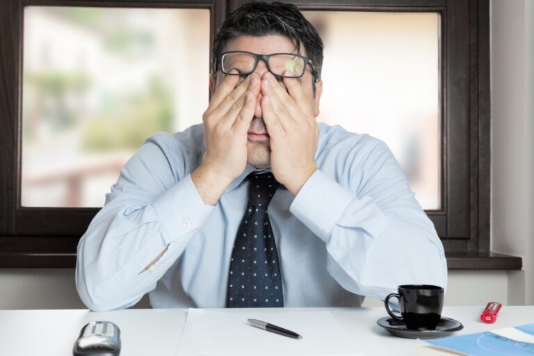 decepção no trabalho - homem com semblante estressado com as mãos nos olhos